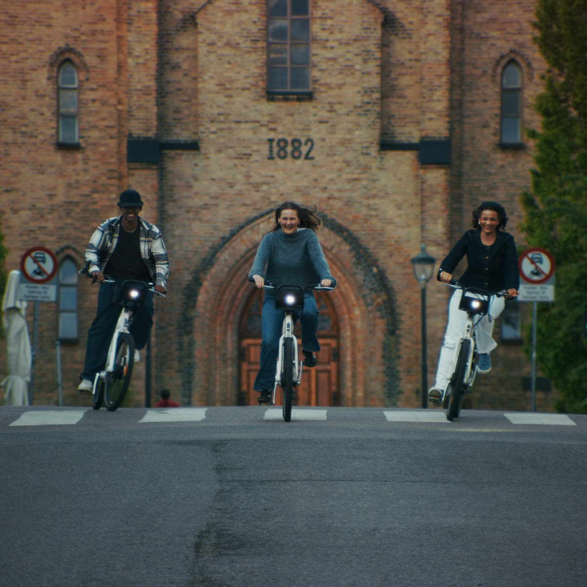 Three cyclists riding through a brick archway in central Oslo