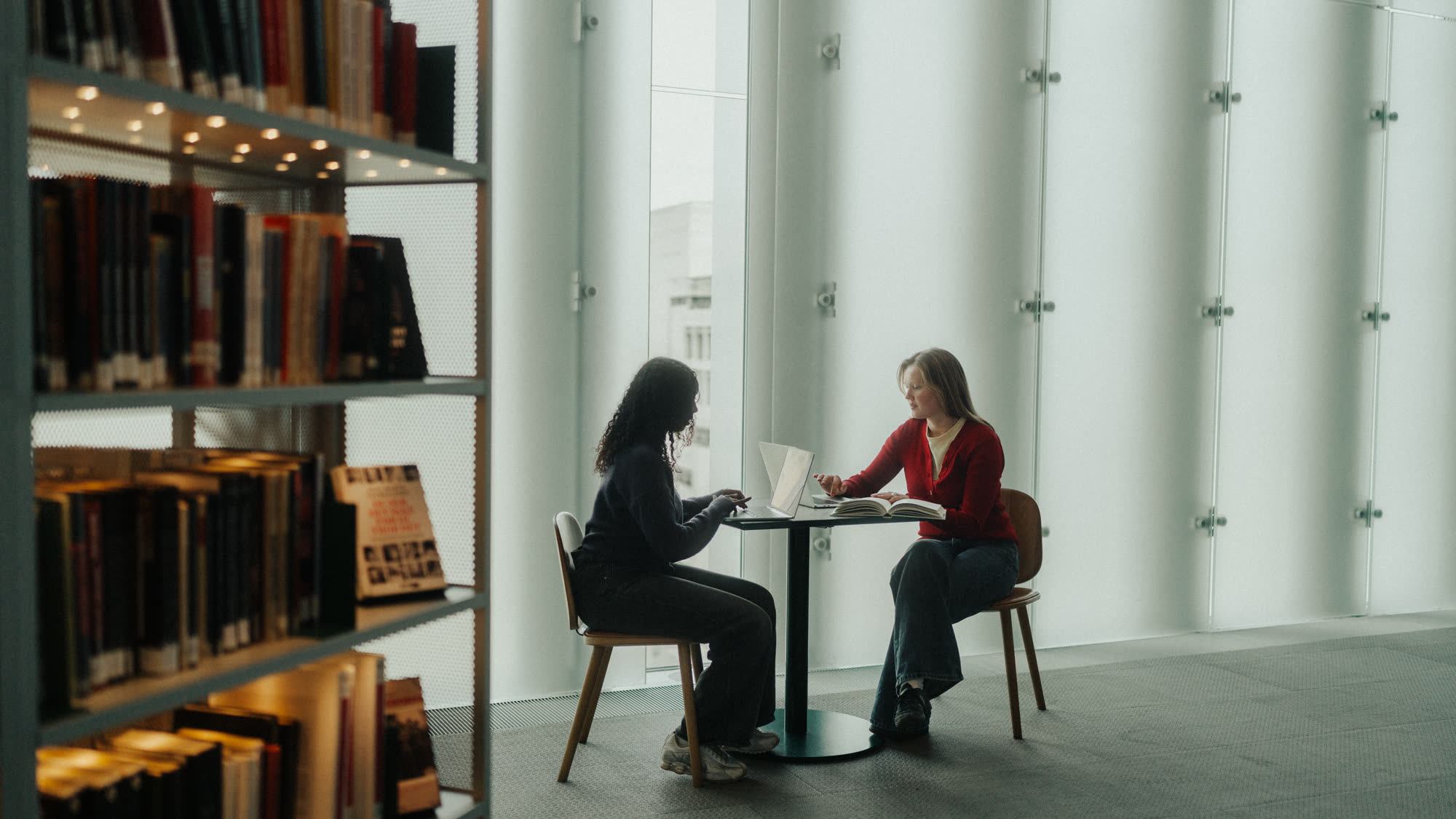 Two people working together at a table in a library